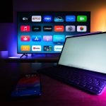 Televisão e tablet exibem aplicativos de streaming em uma sala de estar moderna.