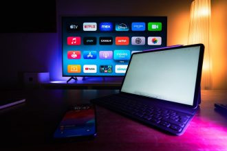 Televisão e tablet exibem aplicativos de streaming em uma sala de estar moderna.
