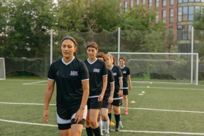 Jogadoras de futebol treinam em um campo durante o dia.