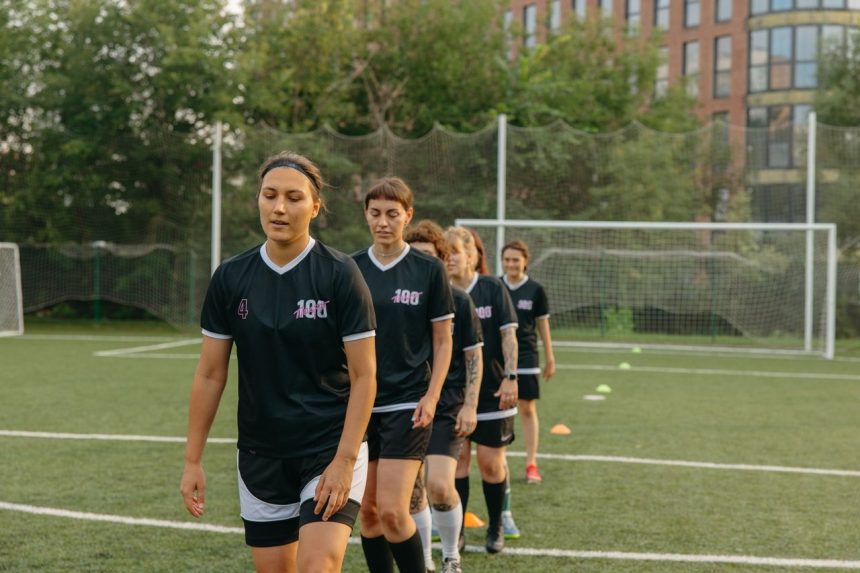 Jogadoras de futebol treinam em um campo durante o dia.